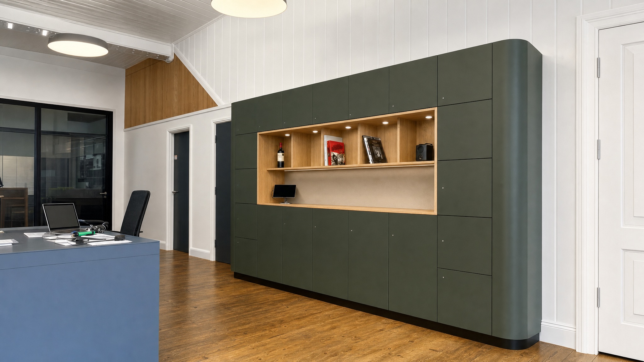 Wall of dark green lockers with central open wood display shelf and spotlights.