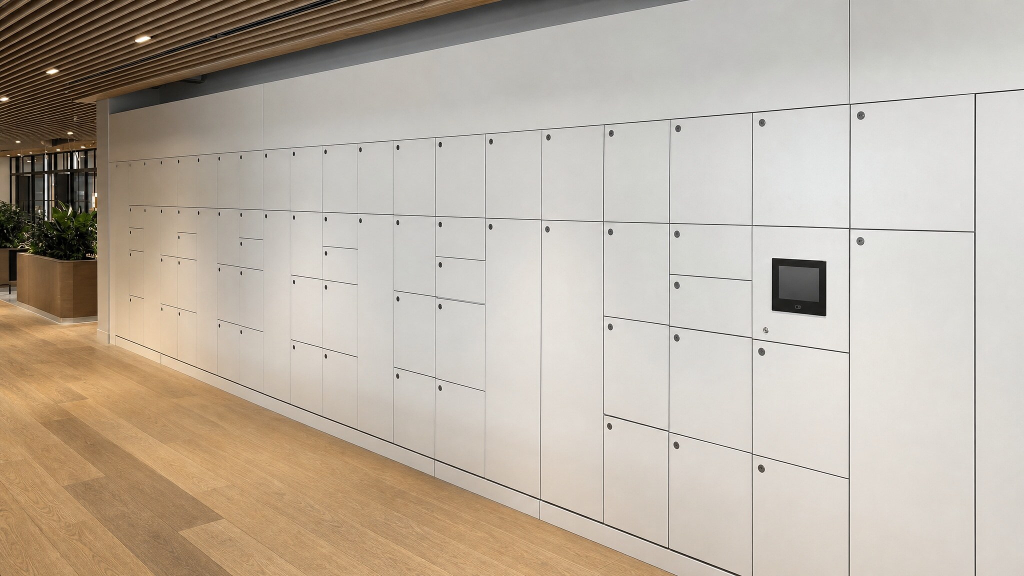Wall of light gray lockers with a small integrated display in a modern hallway.