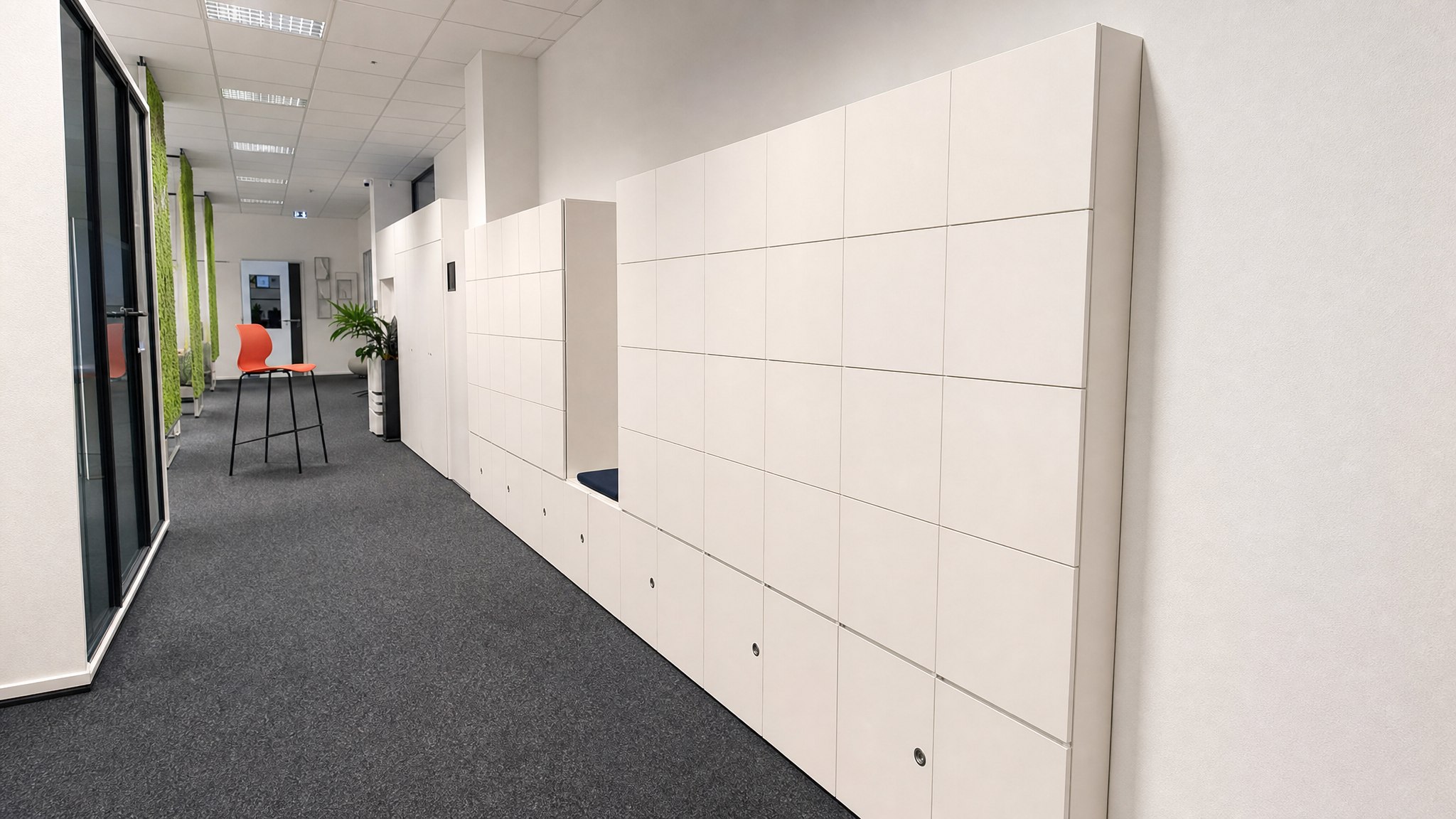 Two banks of light-colored lockers with inset handles in a carpeted hallway.