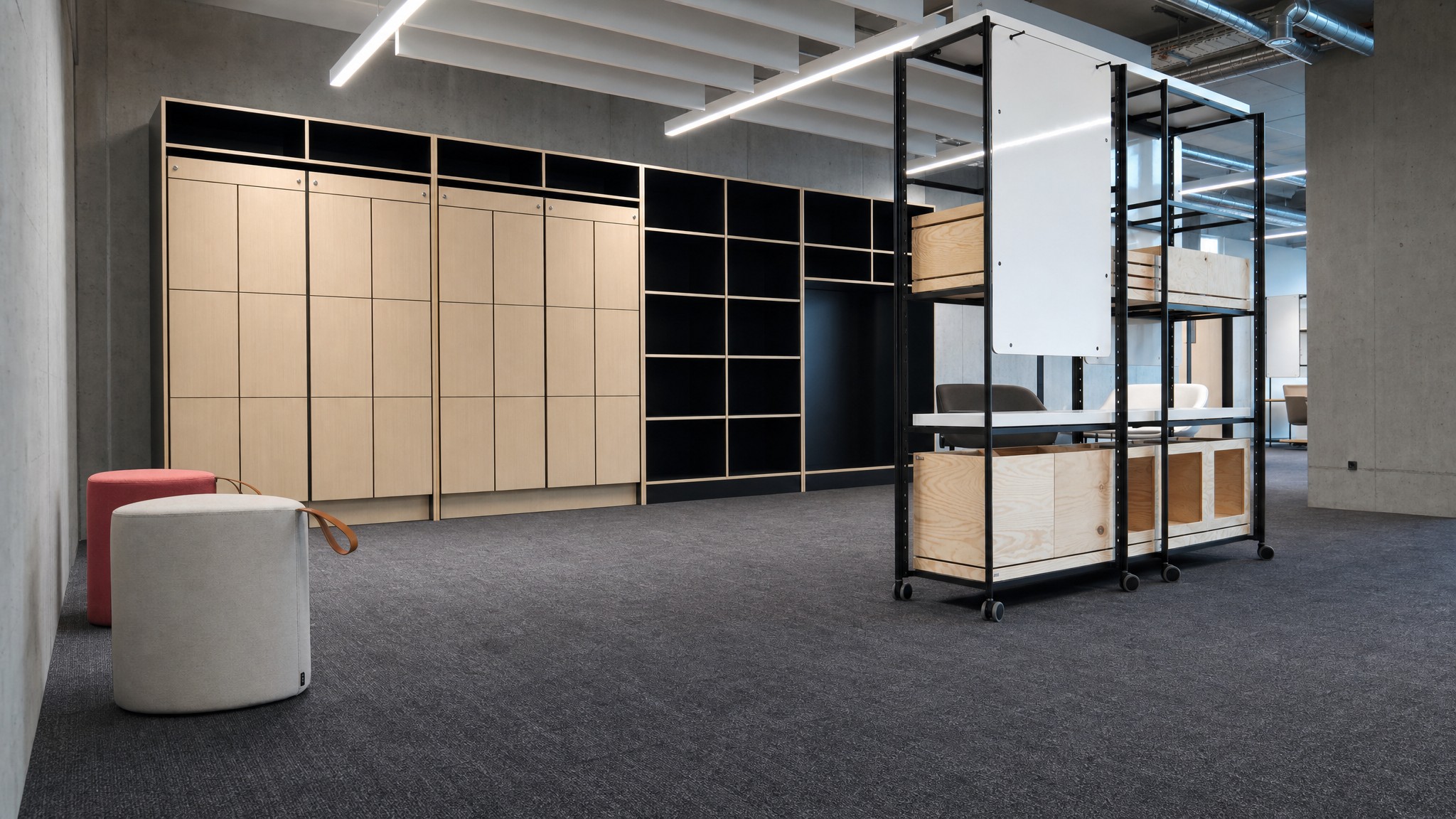 Light wood locker bank and open black shelving against a concrete wall in a modern room.