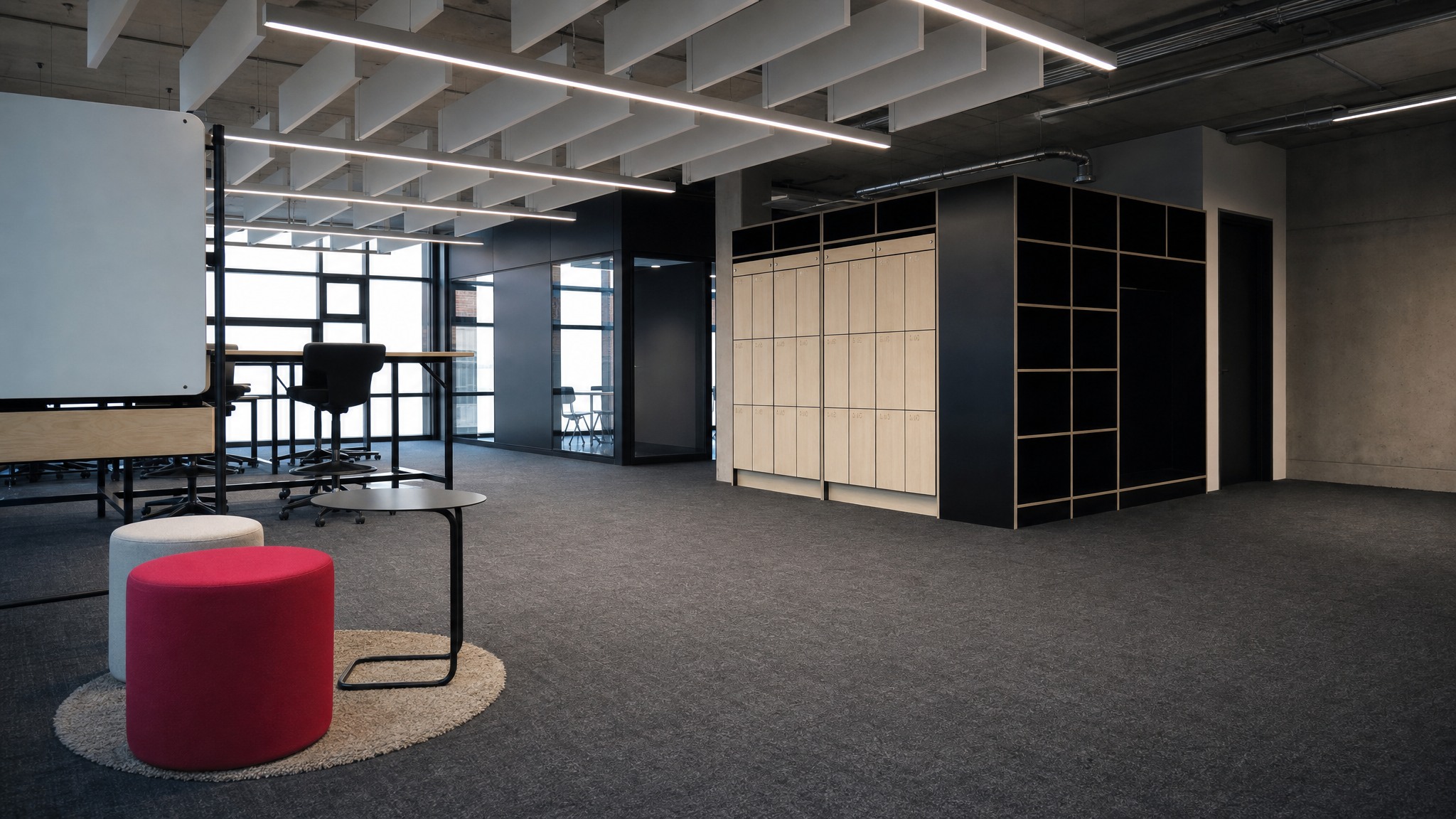 Wall of light wood lockers and open black cubbies in a modern office with seating.