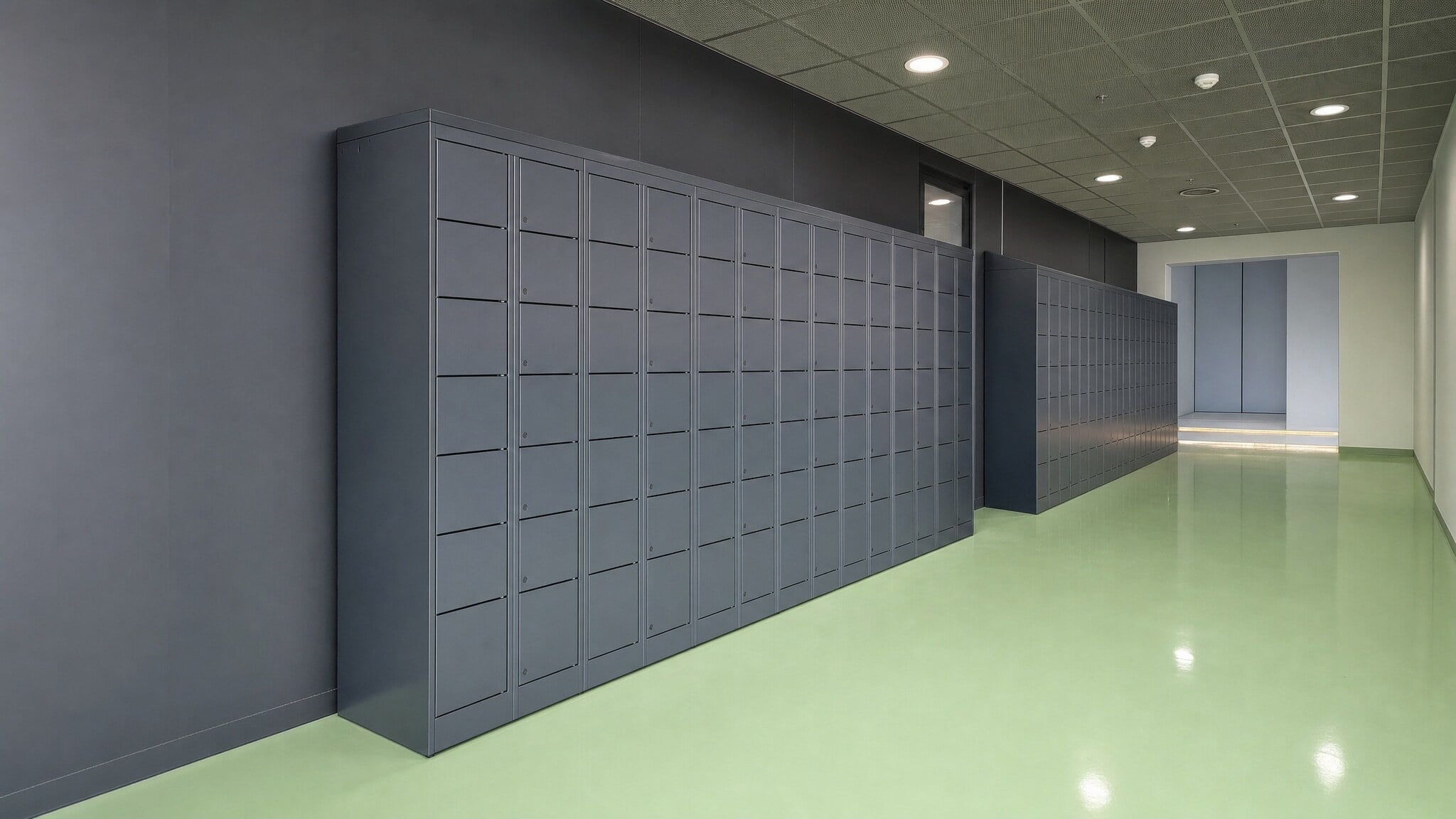 Rows of dark gray keyless lockers in a medical facility hallway