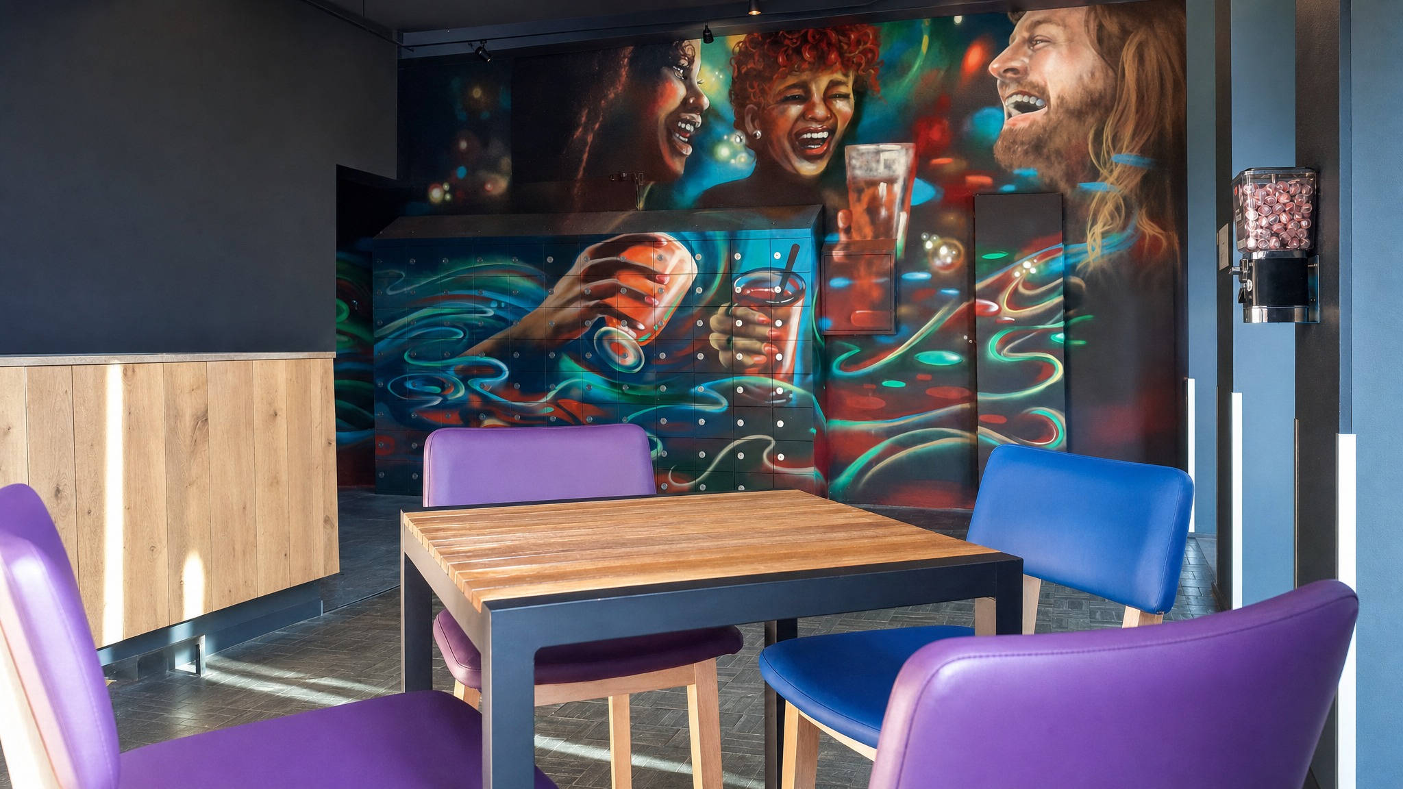 Colorful keyless lockers integrated into wall with vibrant mural in office breakroom