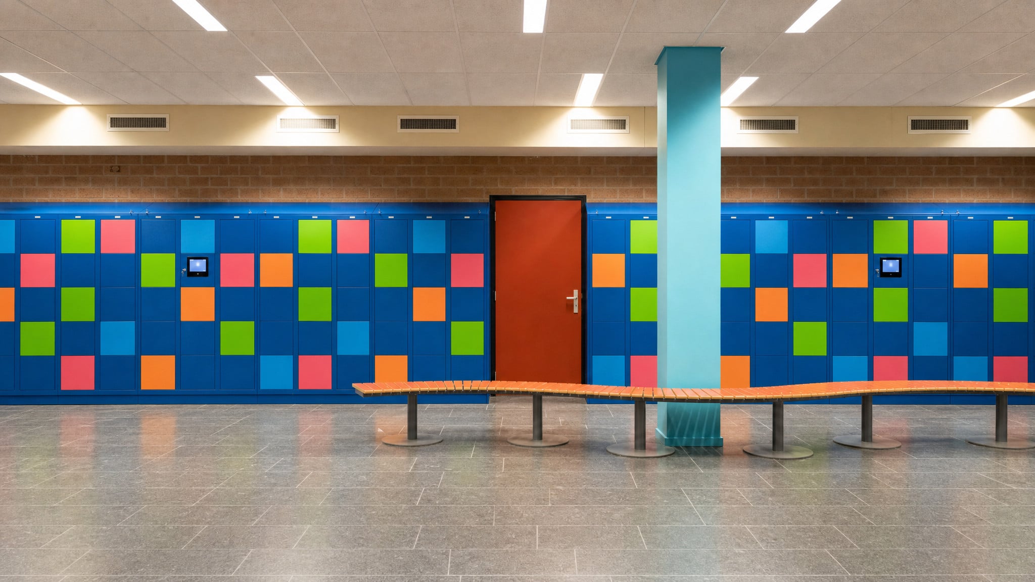 Wall of blue lockers with colorful square doors and two built-in display screens.