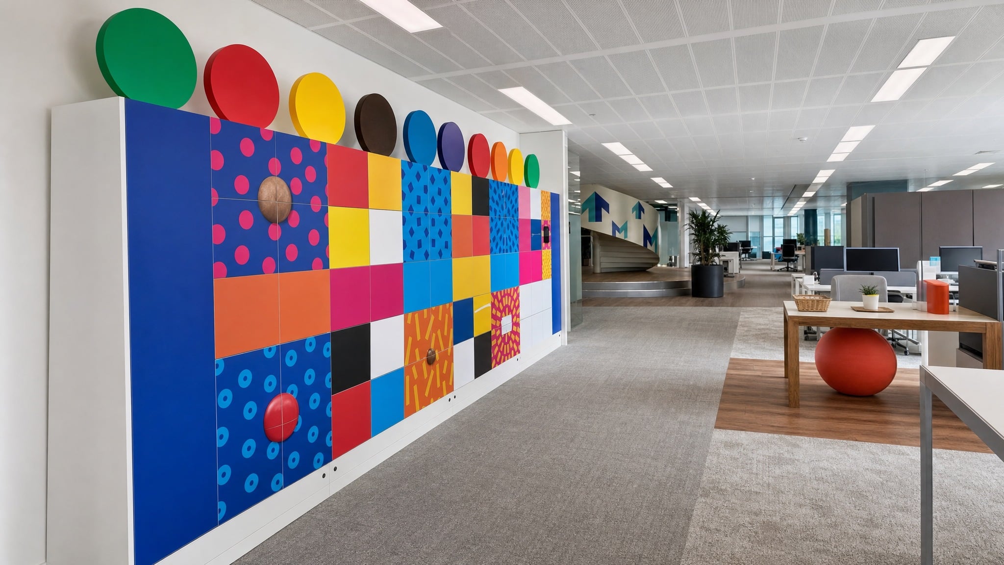 Colorful locker wall with large circular decorations in a modern open office space.