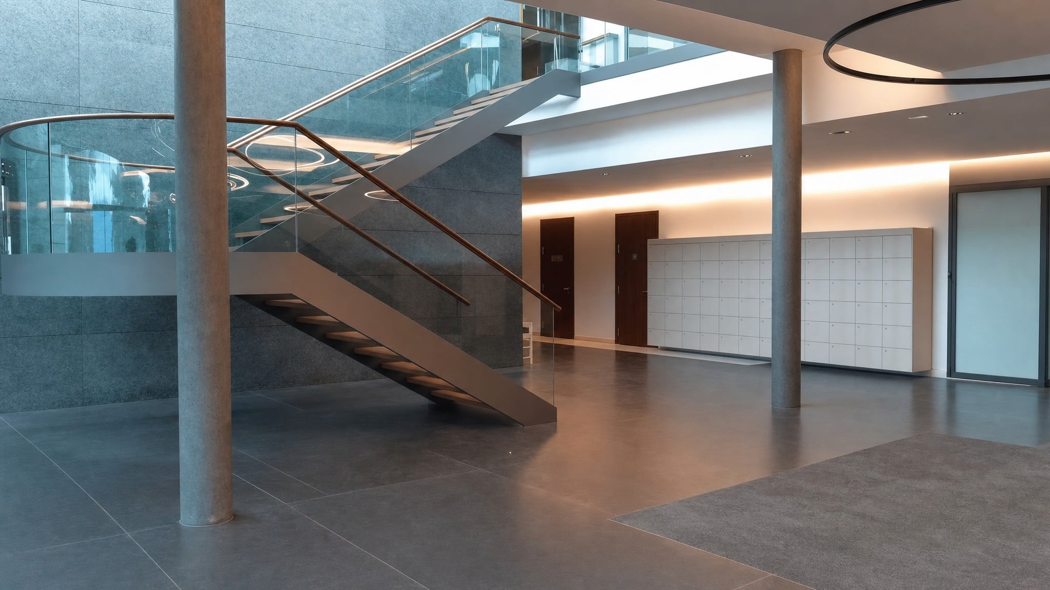 Modern office lobby with glass and metal staircase and white smart parcel lockers